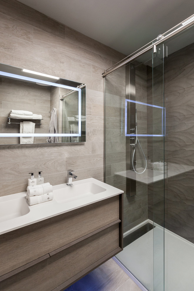 This is an example of a small contemporary 3/4 bathroom in Dallas with an integrated sink, flat-panel cabinets, light wood cabinets, an alcove shower, a two-piece toilet, gray tile, porcelain tile, grey walls, porcelain floors and solid surface benchtops.