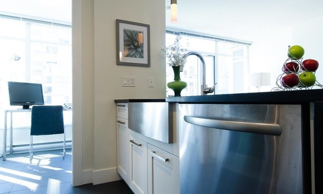 Photo of a small contemporary single-wall open plan kitchen in Vancouver with a farmhouse sink, shaker cabinets, white cabinets, terrazzo benchtops, stainless steel appliances, porcelain floors and with island.
