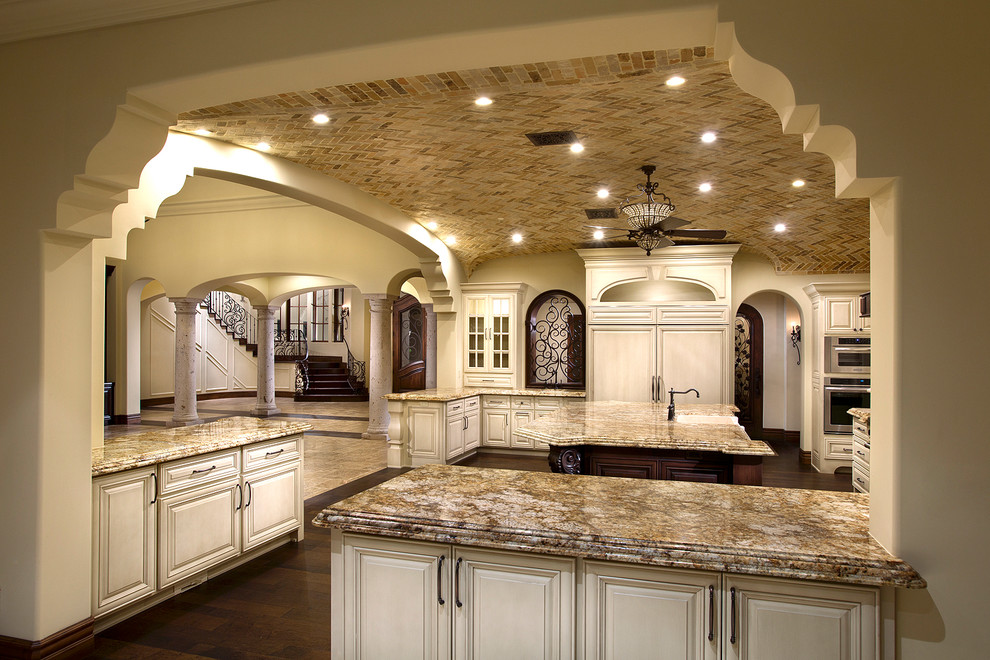 Inspiration for a huge rustic u-shaped dark wood floor and brown floor enclosed kitchen remodel in Phoenix with a farmhouse sink, raised-panel cabinets, light wood cabinets, quartzite countertops, white backsplash, subway tile backsplash, stainless steel appliances, two islands and beige countertops