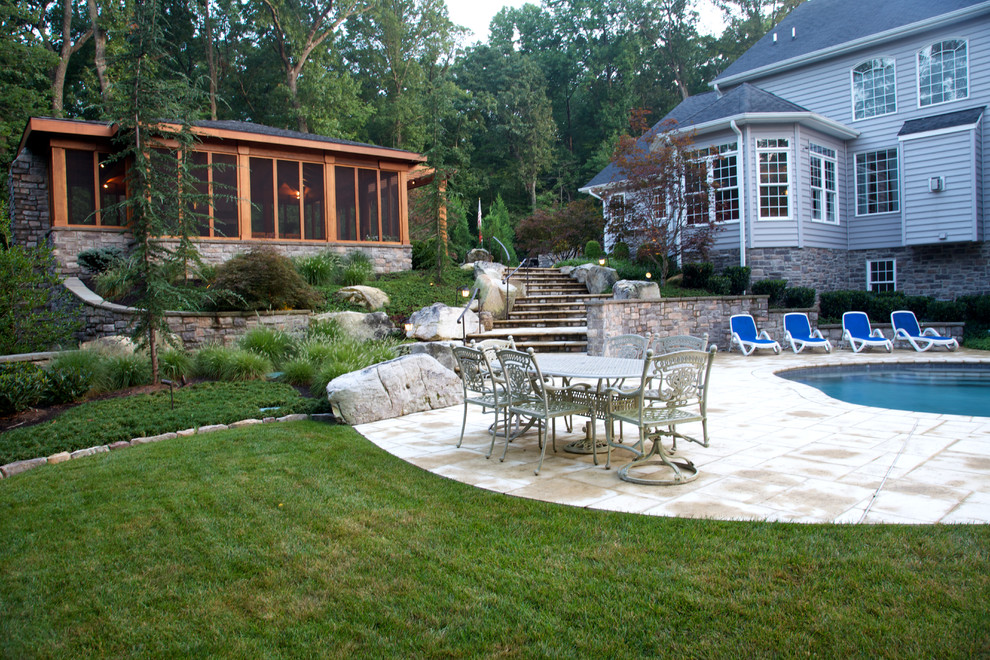 Large traditional backyard full sun garden in DC Metro with a retaining wall and concrete pavers.