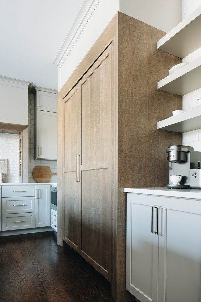 Mid-sized transitional dark wood floor eat-in kitchen photo in Chicago with a farmhouse sink, shaker cabinets, gray cabinets, quartz countertops, white backsplash, ceramic backsplash, paneled appliances, an island and white countertops