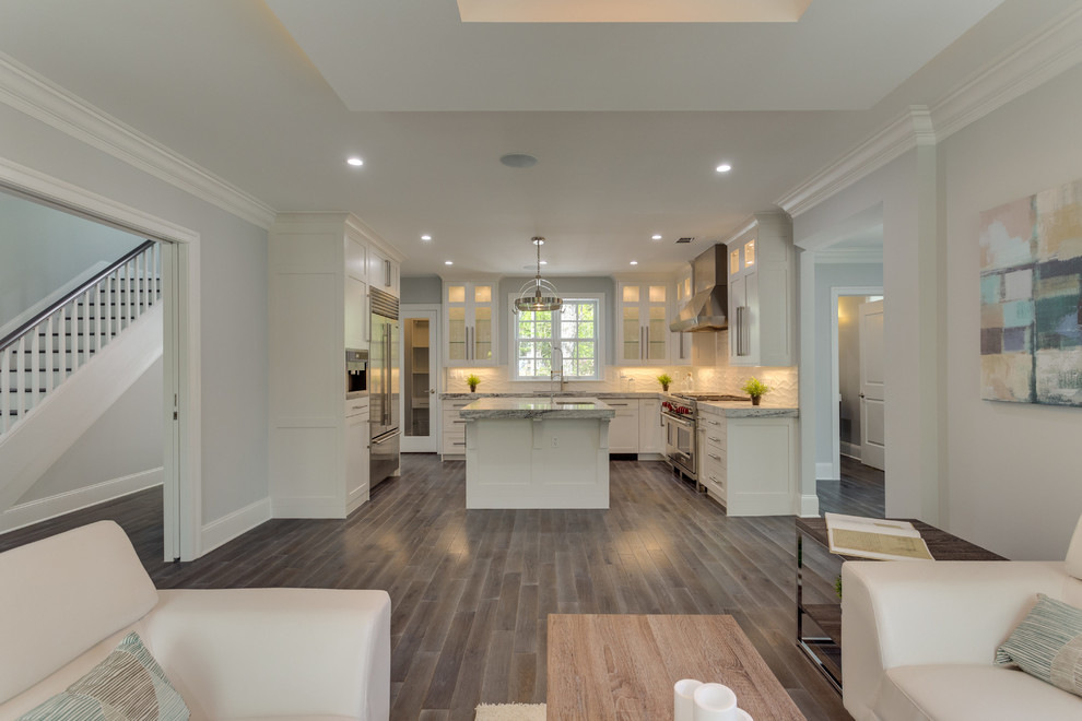 Example of a large transitional l-shaped medium tone wood floor open concept kitchen design in DC Metro with a double-bowl sink, shaker cabinets, white cabinets, marble countertops, white backsplash, porcelain backsplash, stainless steel appliances and an island