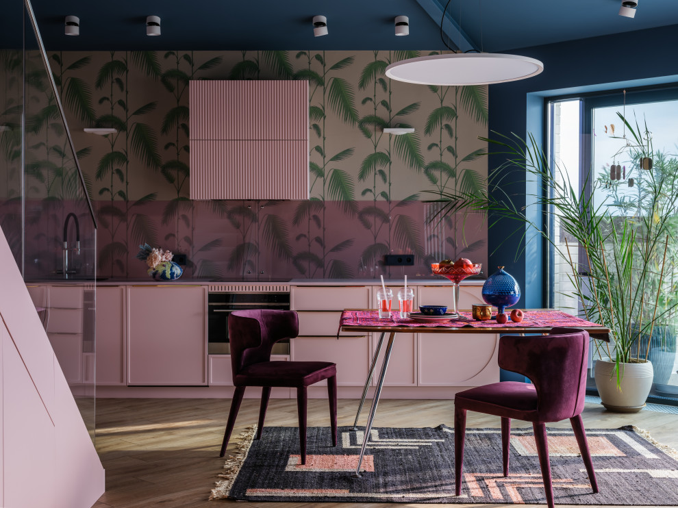 This is an example of a large bohemian l-shaped open plan kitchen in Moscow with a submerged sink, raised-panel cabinets, pink cabinets, concrete worktops, pink splashback, glass sheet splashback, black appliances, light hardwood flooring, no island, brown floors, pink worktops and exposed beams.