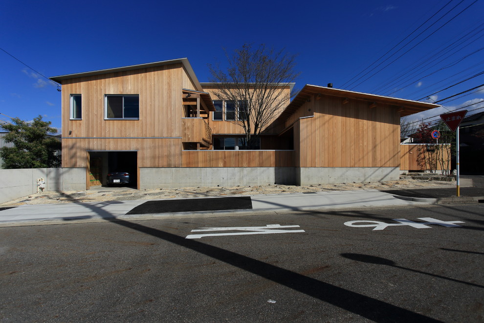 Mid-sized scandinavian two-storey house exterior in Nagoya with wood siding, a shed roof and a metal roof.
