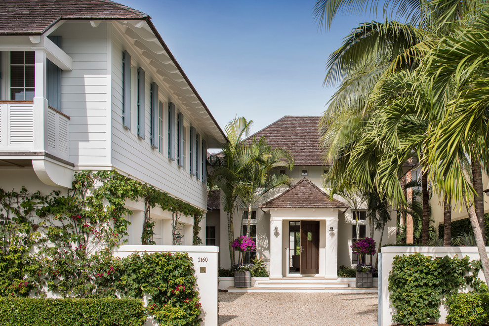 This is an example of a tropical two-storey white exterior in Miami with a hip roof.