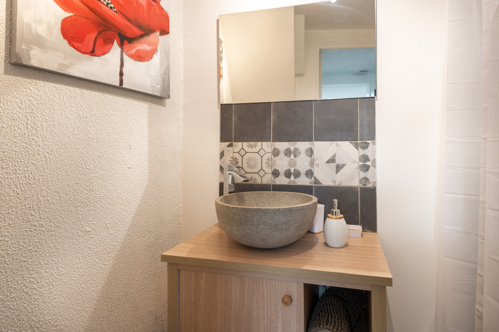 Photo of a small scandinavian master bathroom in Lille with beaded inset cabinets, beige cabinets, a curbless shower, a one-piece toilet, gray tile, mosaic tile, white walls, plywood floors, a trough sink, wood benchtops, brown floor, a shower curtain, beige benchtops, an enclosed toilet, a single vanity, a floating vanity, recessed and wallpaper.