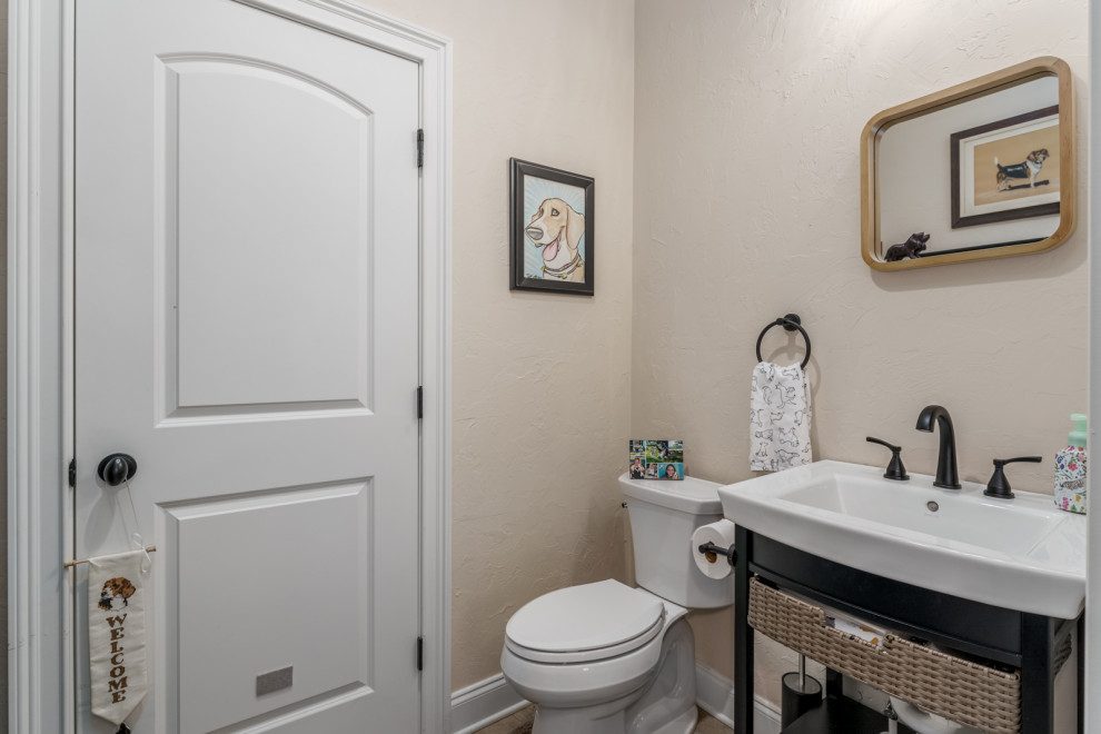Inspiration for a small arts and crafts powder room in Atlanta with a two-piece toilet, beige walls, engineered quartz benchtops, brown floor, white benchtops, open cabinets, black cabinets, vinyl floors, a pedestal sink and a freestanding vanity.