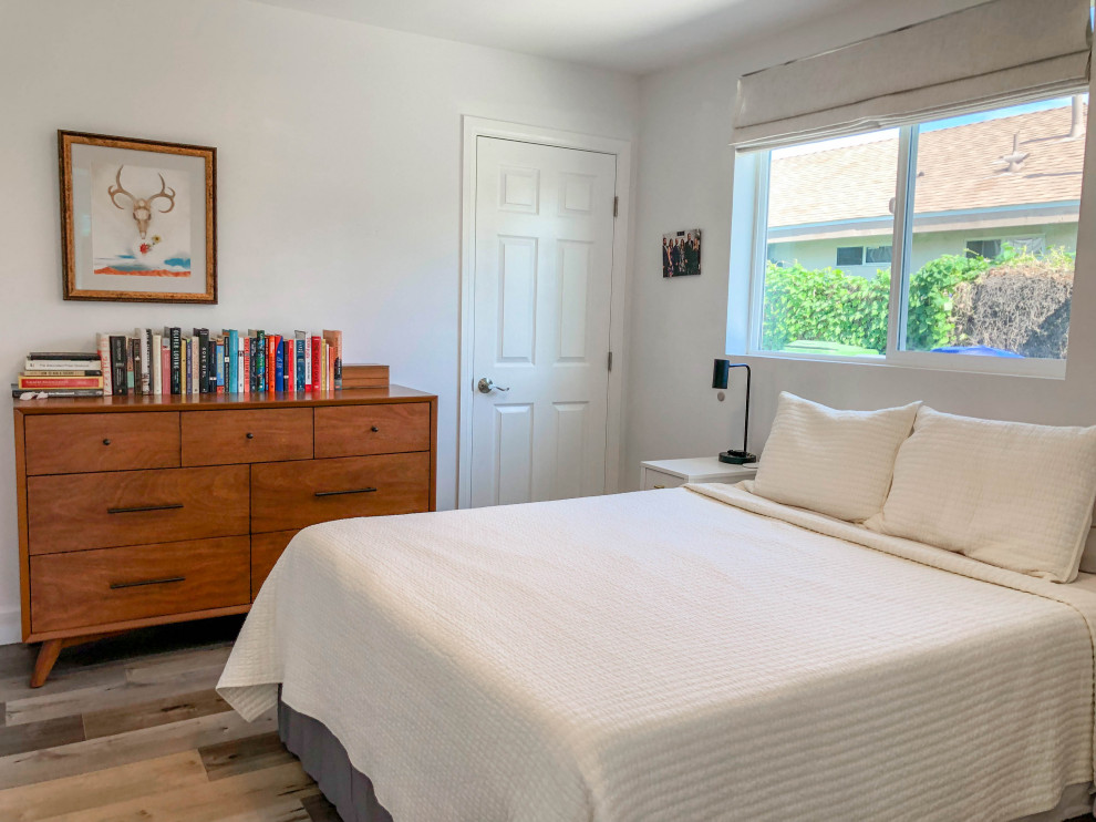 Photo of a mid-sized scandinavian master bedroom in Los Angeles with medium hardwood floors, no fireplace, brown floor and beige walls.