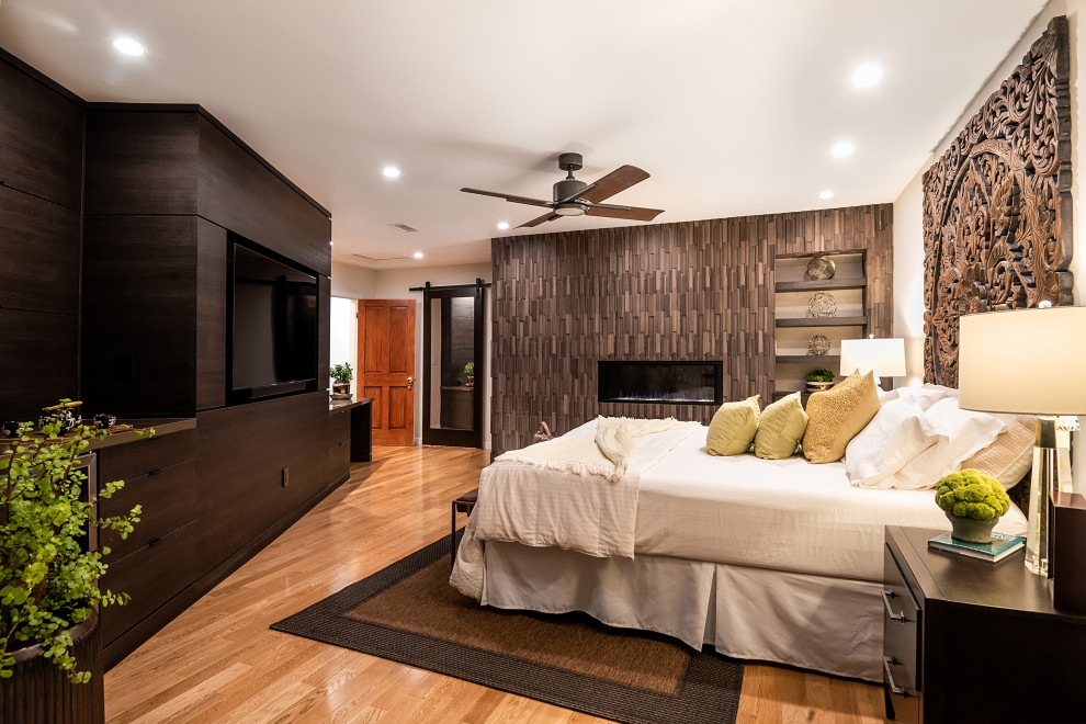 Inspiration for a contemporary bedroom in Los Angeles with beige walls, medium hardwood floors, a ribbon fireplace, a wood fireplace surround, brown floor and wood walls.