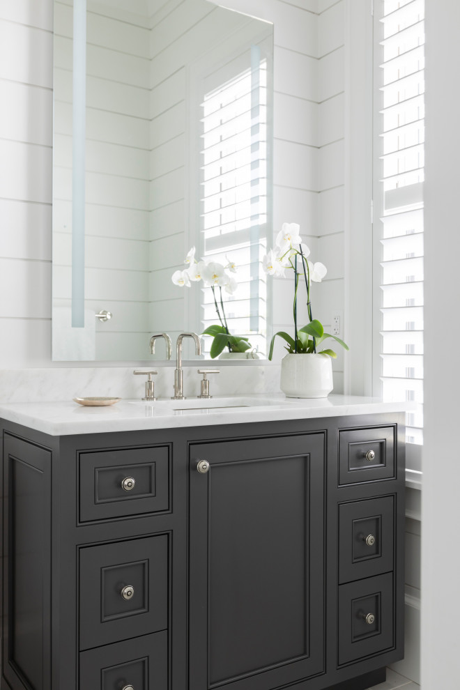 Small beach style 3/4 bathroom in Other with recessed-panel cabinets, black cabinets, white tile, white walls, an integrated sink, marble benchtops, beige floor, white benchtops, a double vanity, a built-in vanity, timber and planked wall panelling.