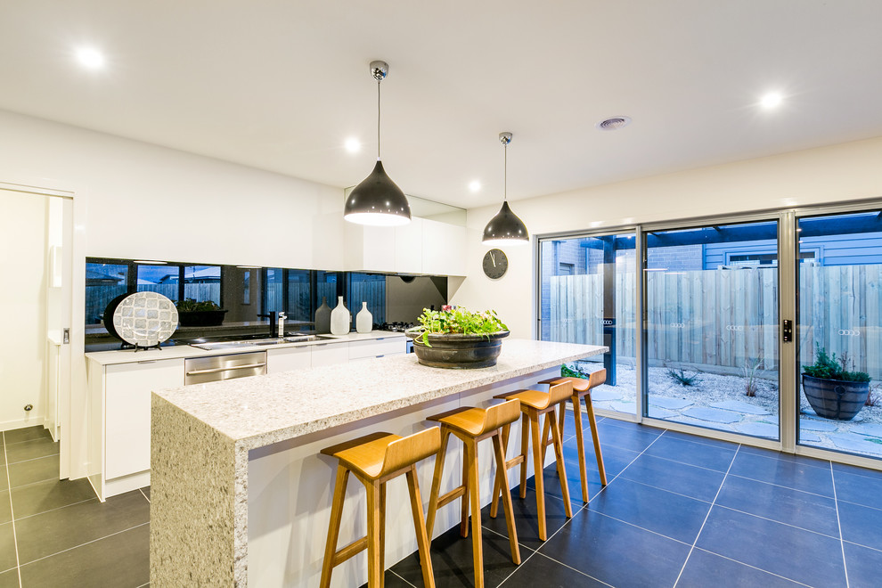 Design ideas for a contemporary galley eat-in kitchen in Geelong with white cabinets, solid surface benchtops, black splashback, stainless steel appliances, porcelain floors and with island.