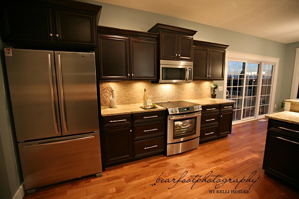 Kitchen - medium tone wood floor kitchen idea in Chicago with an undermount sink, shaker cabinets, black cabinets, granite countertops, brown backsplash and stainless steel appliances