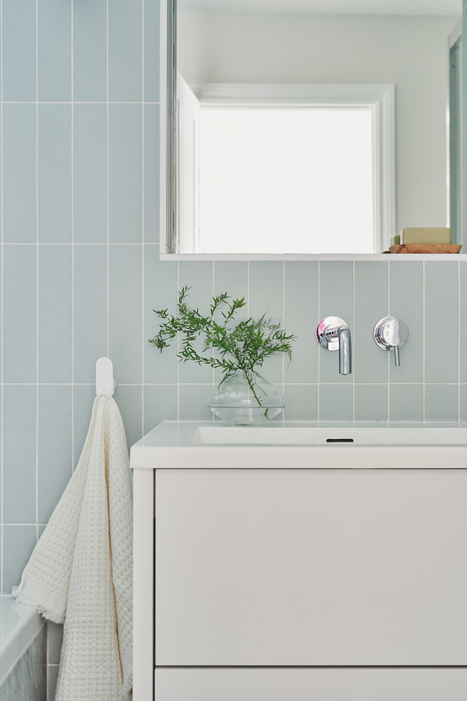 Modern inredning av ett litet vit vitt badrum för barn, med släta luckor, vita skåp, ett platsbyggt badkar, en kantlös dusch, en vägghängd toalettstol, grön kakel, porslinskakel, vita väggar, klinkergolv i porslin, ett integrerad handfat, bänkskiva i akrylsten, grått golv och dusch med skjutdörr