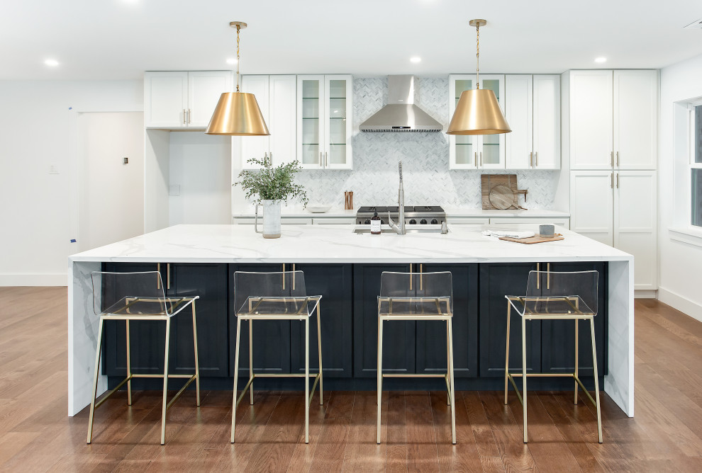 Inspiration for a large contemporary single-wall open plan kitchen in Dallas with an undermount sink, shaker cabinets, white cabinets, quartz benchtops, white splashback, marble splashback, stainless steel appliances, medium hardwood floors, with island, brown floor and white benchtop.