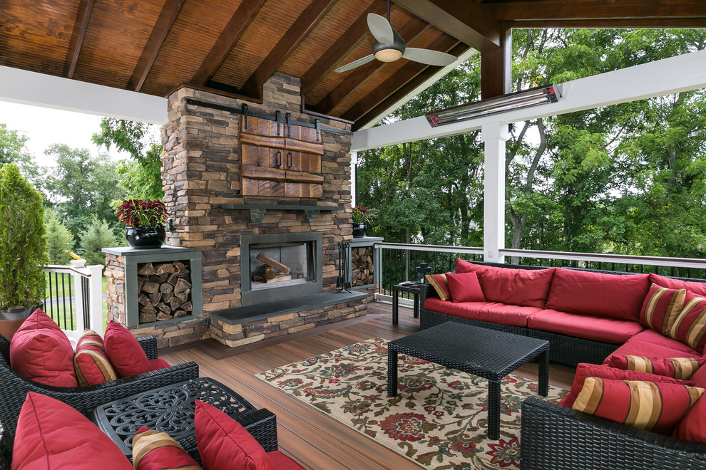 Large traditional backyard deck in Baltimore with a fire feature and a roof extension.