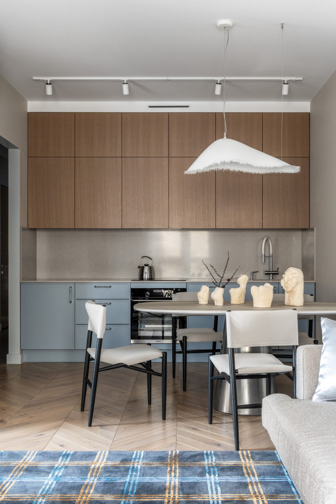Photo of a contemporary single-wall open plan kitchen in Moscow with flat-panel cabinets, blue cabinets, grey splashback, stone slab splashback, black appliances, medium hardwood flooring, no island, brown floors and grey worktops.