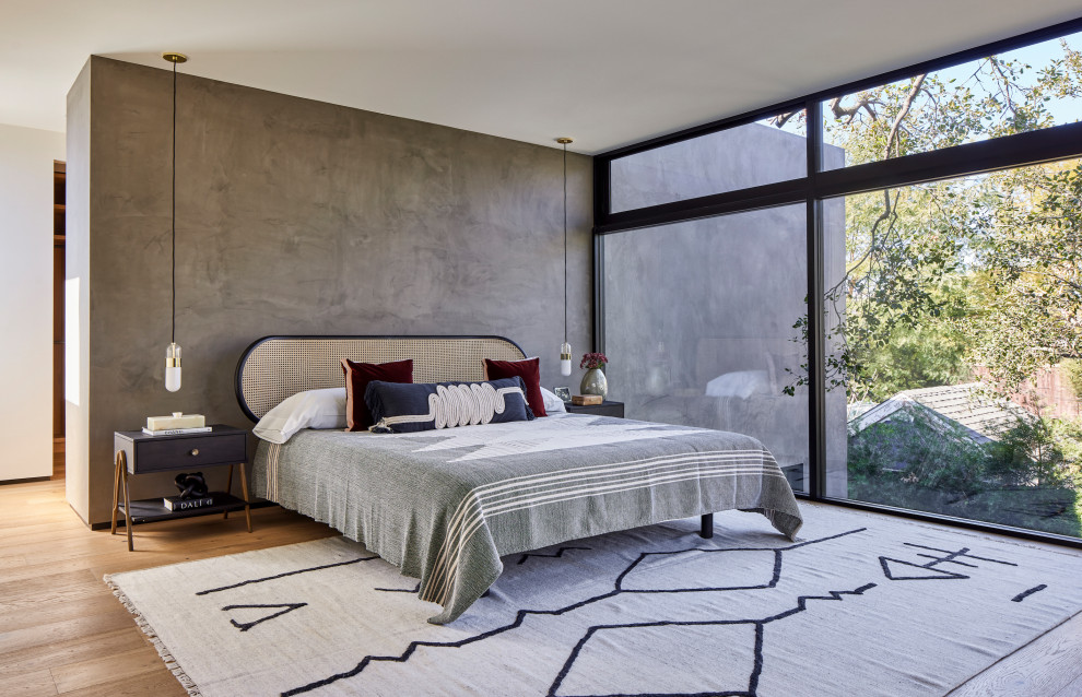 Diseño de dormitorio principal, blanco y gris y negro minimalista grande con paredes grises, suelo de madera clara, chimenea de esquina, marco de chimenea de piedra, suelo beige y todos los tratamientos de pared
