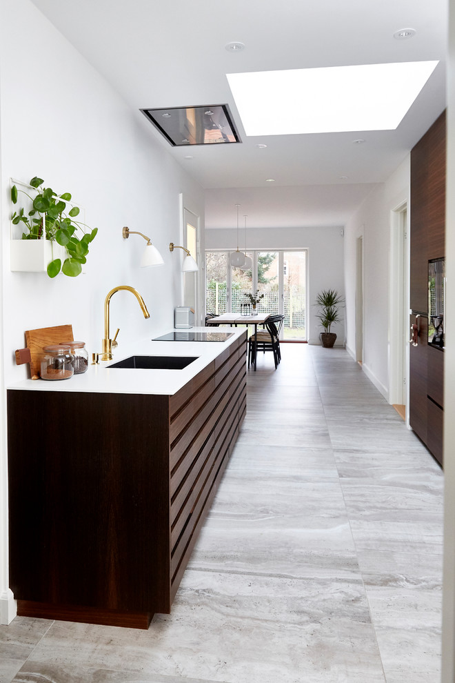 Photo of a mid-sized modern galley open plan kitchen in Copenhagen with an undermount sink, dark wood cabinets, black appliances, ceramic floors, a peninsula and grey floor.