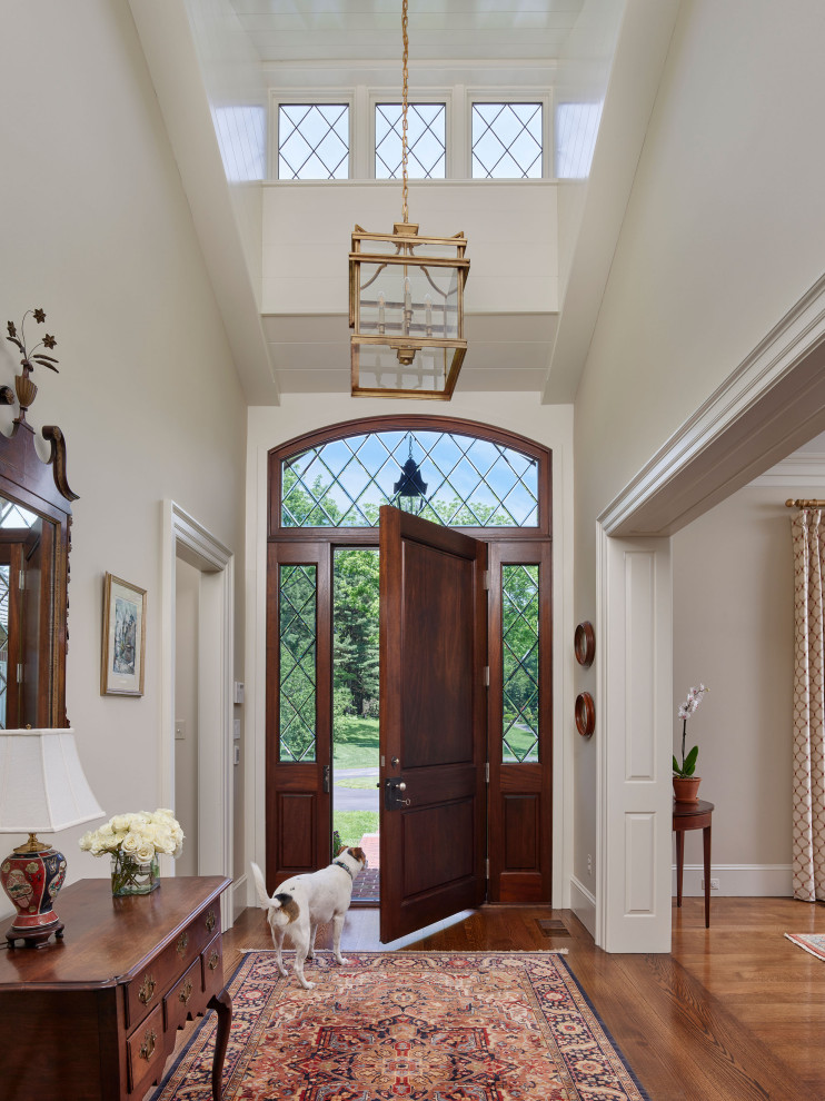 Idee per un ingresso classico con pareti bianche, pavimento in legno massello medio, una porta singola, una porta in legno bruno e soffitto a volta
