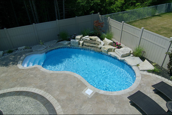 Pool - mid-sized transitional backyard concrete paver and custom-shaped lap pool idea in Toronto