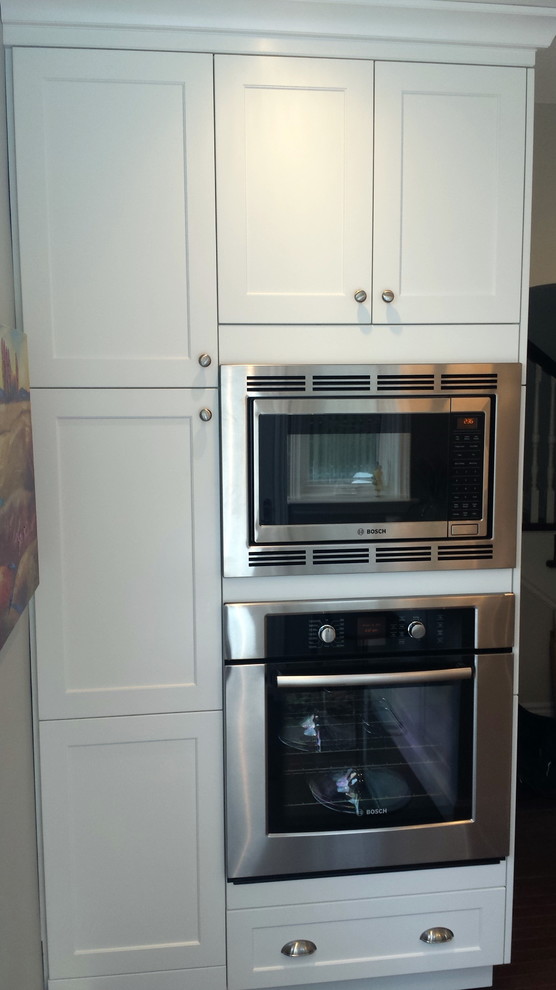 Example of a mid-sized transitional u-shaped dark wood floor enclosed kitchen design in Ottawa with an undermount sink, shaker cabinets, white cabinets, quartz countertops, white backsplash, subway tile backsplash, stainless steel appliances and a peninsula