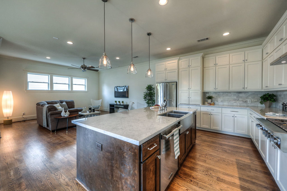 Inspiration for a mid-sized transitional l-shaped medium tone wood floor and brown floor open concept kitchen remodel in Houston with shaker cabinets, white cabinets, an island, a farmhouse sink, marble countertops, gray backsplash, marble backsplash, stainless steel appliances and gray countertops