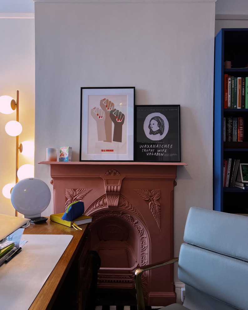 Eklektisk inredning av ett mellanstort arbetsrum, med rosa väggar, mellanmörkt trägolv, en standard öppen spis, en spiselkrans i metall, ett fristående skrivbord och brunt golv
