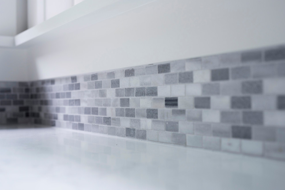 Example of a mid-sized transitional u-shaped vinyl floor and multicolored floor kitchen design with an undermount sink, shaker cabinets, brown cabinets, quartz countertops, gray backsplash, marble backsplash, stainless steel appliances, no island and white countertops