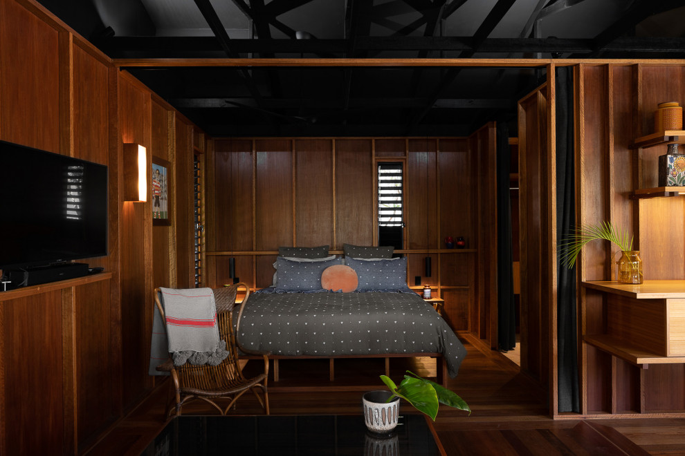Tropical bedroom in Gold Coast - Tweed with brown walls, dark hardwood floors, brown floor and wood walls.