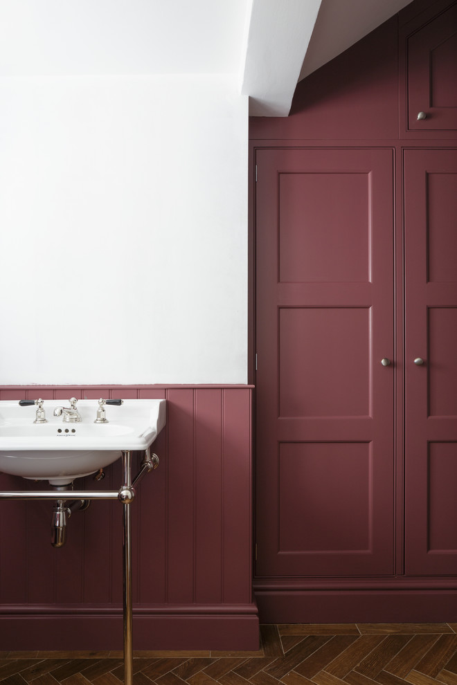 Design ideas for a large traditional powder room in Surrey with beaded inset cabinets, red cabinets, dark hardwood floors, a console sink and brown floor.