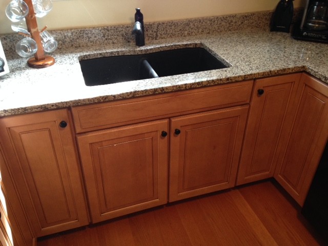 Example of a small transitional u-shaped medium tone wood floor home design design with an undermount sink, raised-panel cabinets, medium tone wood cabinets, granite countertops, black appliances and no island
