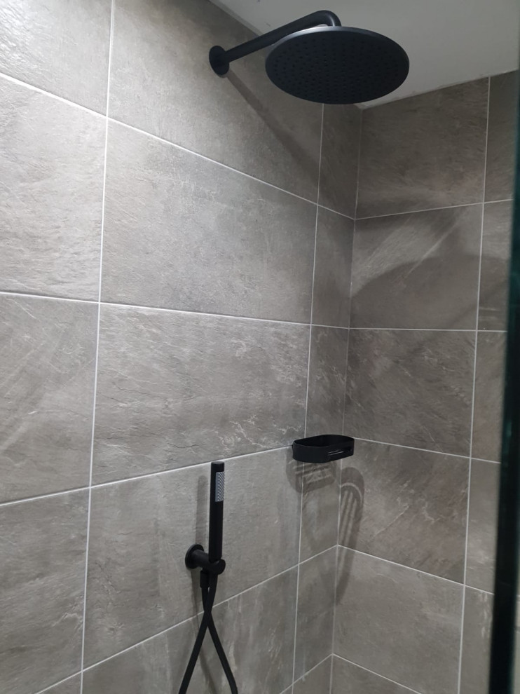 Exempel på ett mellanstort modernt badrum med dusch, med en öppen dusch, en toalettstol med hel cisternkåpa, grå kakel, porslinskakel, grå väggar, klinkergolv i porslin, ett väggmonterat handfat och grått golv