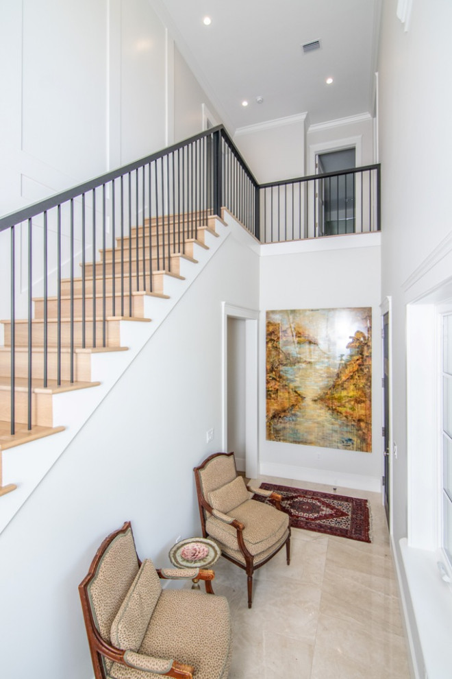 This is an example of a large transitional wood straight staircase in Tampa with wood risers, metal railing and decorative wall panelling.