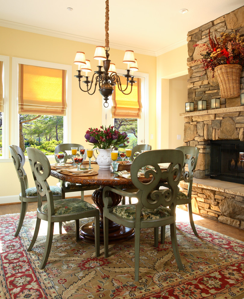 Design ideas for a traditional dining room in San Francisco with yellow walls, dark hardwood floors, a standard fireplace and a stone fireplace surround.