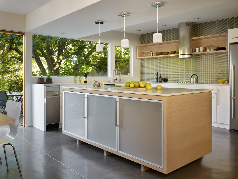 Design ideas for a contemporary l-shaped eat-in kitchen in Seattle with flat-panel cabinets, white cabinets, green splashback, mosaic tile splashback, stainless steel appliances, with island and concrete floors.
