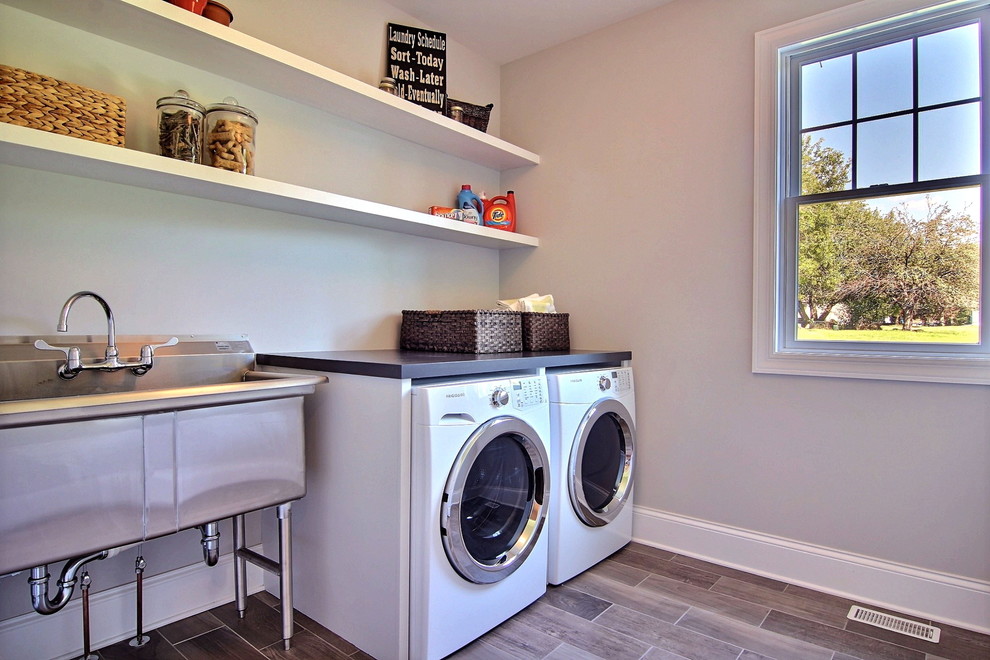 Photo of a mid-sized transitional dedicated laundry room in Chicago with an utility sink, wood benchtops, beige walls, ceramic floors and a side-by-side washer and dryer.