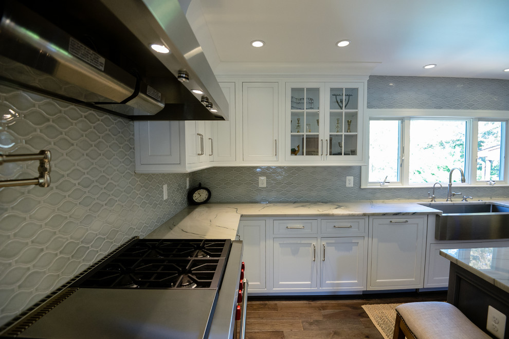 Large transitional u-shaped medium tone wood floor and brown floor eat-in kitchen photo in DC Metro with a farmhouse sink, recessed-panel cabinets, white cabinets, marble countertops, stainless steel appliances, an island and gray backsplash