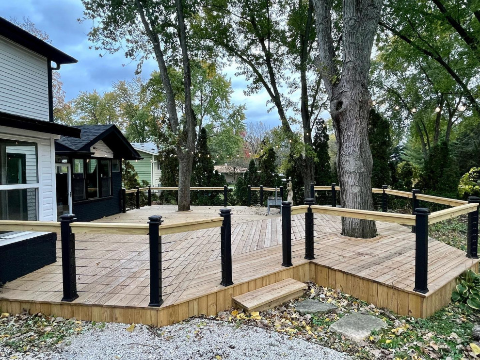 Large backyard ground level wood railing deck photo in Chicago with a fire pit