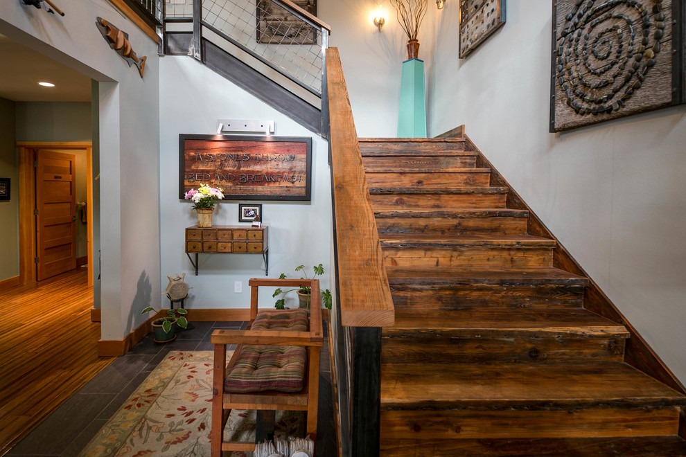 Diseño de escalera en L rústica grande con escalones de madera, contrahuellas de madera y barandilla de metal