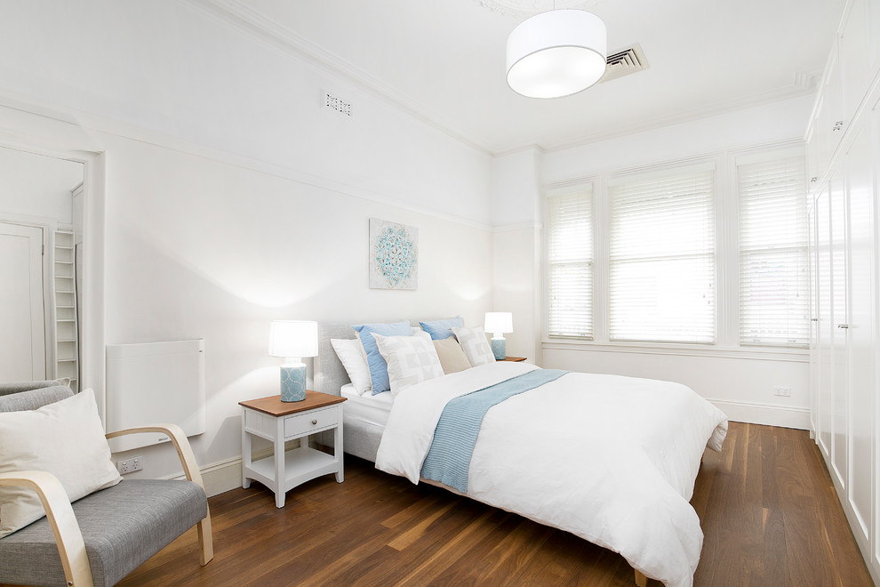 Photo of a modern guest bedroom in Sydney with white walls, medium hardwood floors, no fireplace and brown floor.