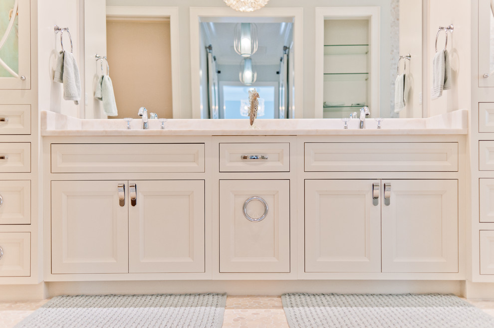 This is an example of a mid-sized beach style master bathroom in Jacksonville with beaded inset cabinets, white cabinets, white tile, glass sheet wall, white walls, pebble tile floors and marble benchtops.