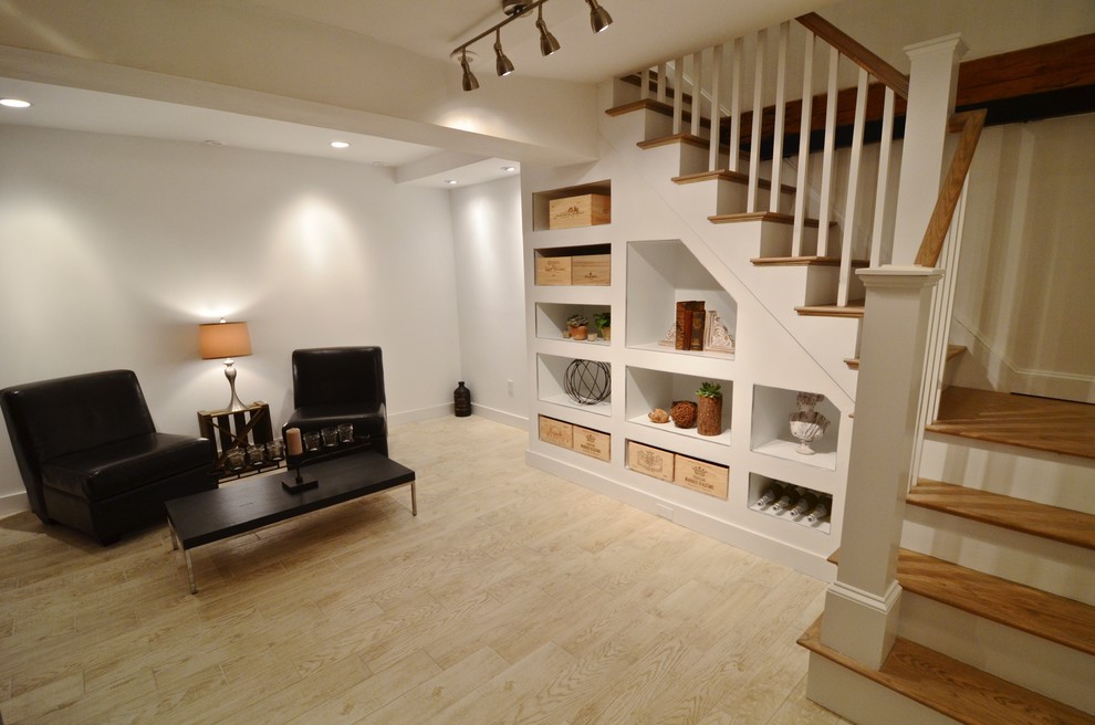 This is an example of a mid-sized country fully buried basement in Boston with white walls, light hardwood floors, no fireplace and brown floor.