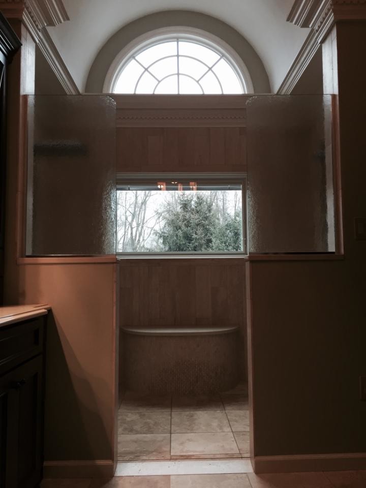 Doorless shower - mid-sized transitional master travertine floor and beige floor doorless shower idea with shaker cabinets, brown cabinets, beige walls, an undermount sink and quartz countertops