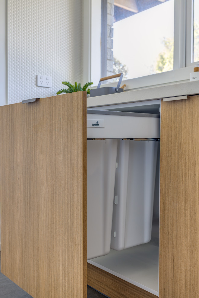 Small scandinavian galley dedicated laundry room in Melbourne with a drop-in sink, open cabinets, light wood cabinets, quartz benchtops, white walls, medium hardwood floors, a side-by-side washer and dryer and white benchtop.