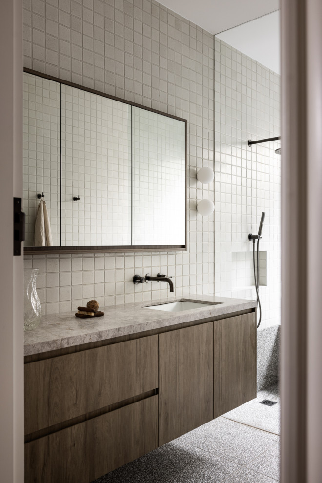 Идея дизайна: ванная комната в стиле модернизм с плоскими фасадами, фасадами цвета дерева среднего тона, душем без бортиков, белой плиткой, врезной раковиной, серым полом, серой столешницей, тумбой под одну раковину и подвесной тумбой
