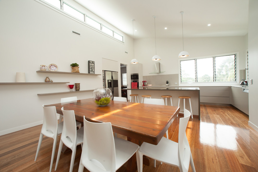 This is an example of a mid-sized contemporary kitchen/dining combo in Brisbane with white walls and medium hardwood floors.