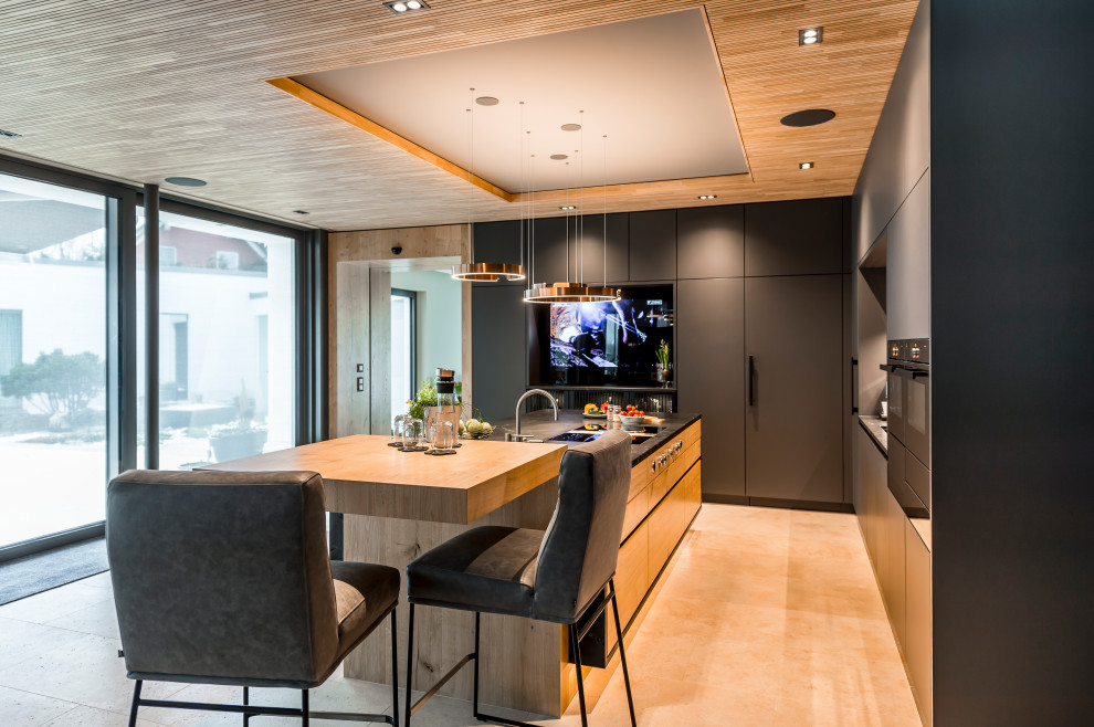 Photo of a large contemporary l-shaped open plan kitchen in Leipzig with an undermount sink, grey cabinets, grey splashback, stone slab splashback, black appliances, with island, beige floor, grey benchtop and wood.