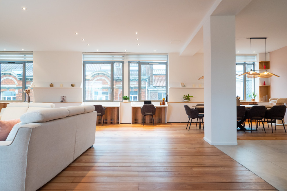 Example of a large danish open concept medium tone wood floor living room design in Lille with white walls and no fireplace