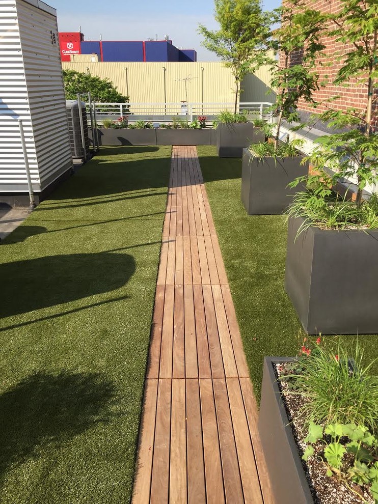 This is an example of a large traditional rooftop partial sun formal garden for summer in New York with a container garden and decking.