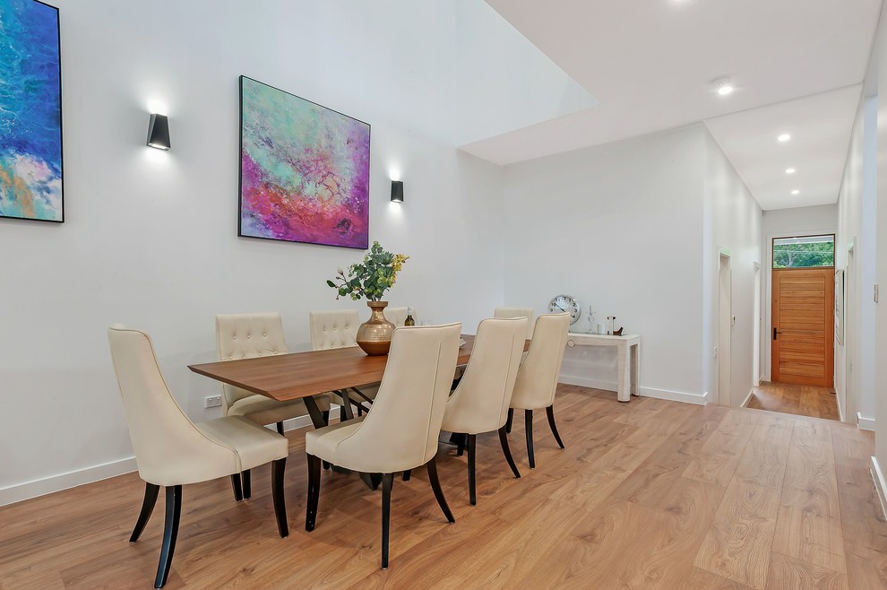 Photo of a contemporary dining room in Sydney with white walls, medium hardwood floors and brown floor.